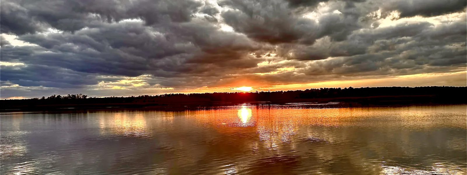 Sunset breaking through storm clouds over still water in coastal Georgia